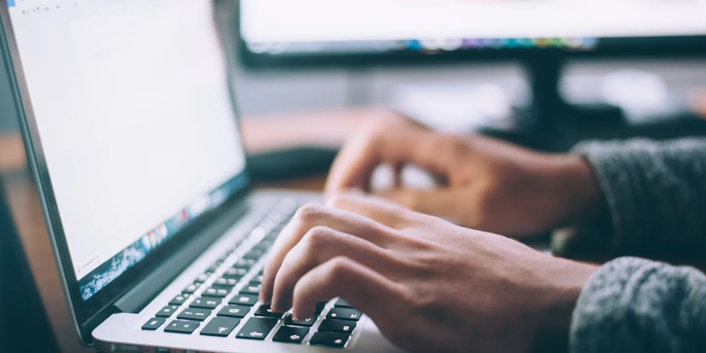 Manos escribiendo en el teclado de un portátil durante el desarrollo de una web